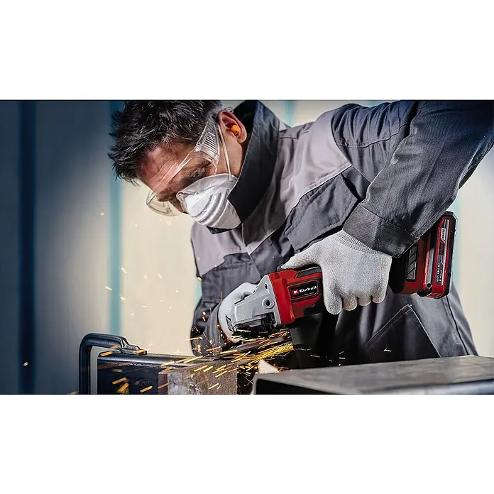 Einhell Professional PXC 18V Amoladora angular de batería TP-AG 18/125 CE Q Li - Solo - Sin batería, Diámetro disco: 125 cm, 3.000 r.p.m. - 10.500 r.p.m. - Primer plano de un hombre esmerilando metales con una amoladora angular inalámbrica Einhell roja, con gafas de seguridad y mascarilla antipolvo.