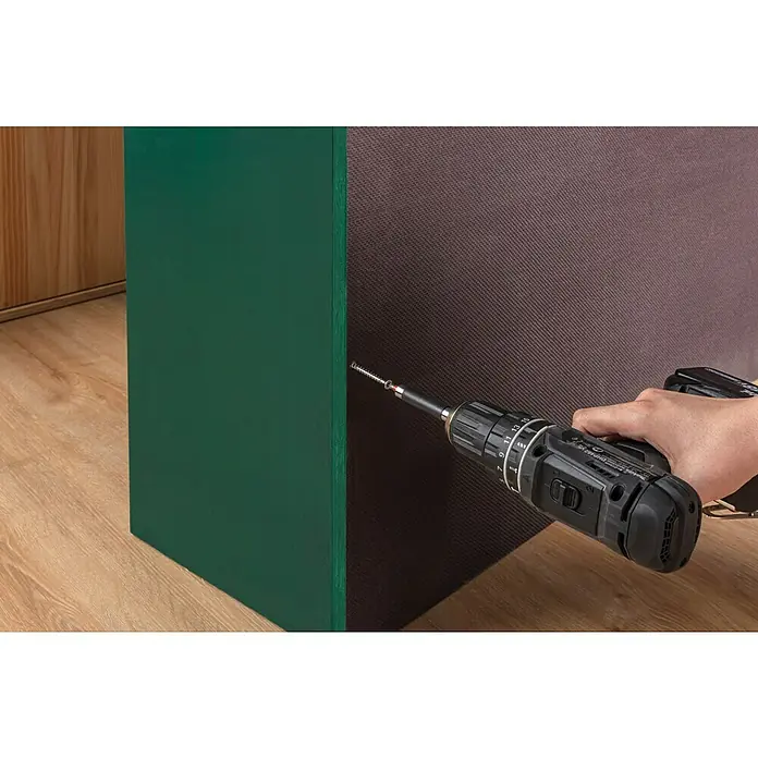 swingcolor Buntlack Acryl - Moosgrün, Seidenmatt, 375 ml, Wasserbasiert - Ein Akkuschrauber befestigt eine Schraube in ein grünes Holzstück, Teil eines Möbelstücks, auf einem hölzernen Boden.