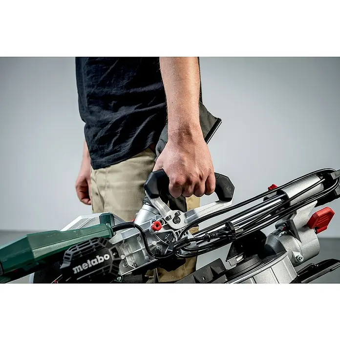 Metabo Kapp- & Gehrungssäge KGS 216 M Set - 1.500 W, Durchmesser Sägeblatt: 216 mm, Leerlaufdrehzahl: 5.000 U/min - Nahaufnahme einer Metabo Kapp- und Gehrungssäge, die von einer Person gehalten wird, ideal für präzise Holzarbeiten und professionelle Schnitte.