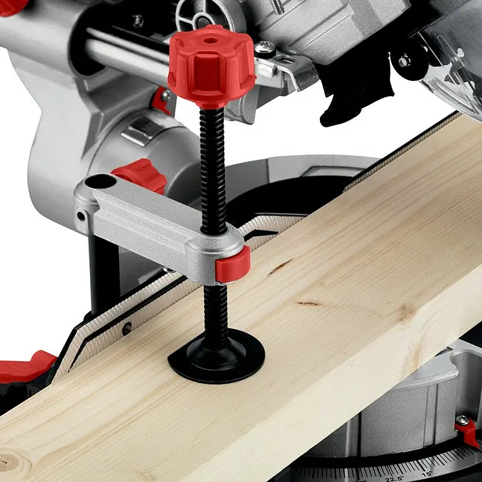 Metabo Kapp- & Gehrungssäge KGS 216 M Set - 1.500 W, Durchmesser Sägeblatt: 216 mm, Leerlaufdrehzahl: 5.000 U/min - Nahaufnahme einer Kapp- und Gehrungssäge mit einer Holzlatte, die mit einer roten Klemme befestigt ist.