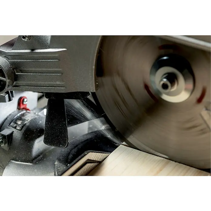 Metabo Kapp- & Gehrungssäge KS 216 M - 1.100 W, Durchmesser Sägeblatt: 216 mm, Leerlaufdrehzahl: 5.000 U/min - Nahaufnahme einer Kreissäge in Aktion, die Holz schneidet. Die rotierende Klinge und die Holzspäne sind gut sichtbar.