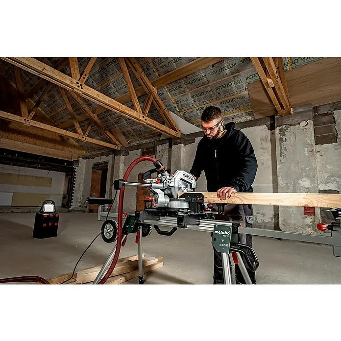 Metabo Kapp- & Gehrungssäge KGS 254 M - 1.800 W, Durchmesser Sägeblatt: 254 mm, Leerlaufdrehzahl: 4.500 U/min - Ein Handwerker bedient eine Metabo Kappsäge mit Zugfunktion zum Zuschneiden eines Holzstücks in einer Baustelle.