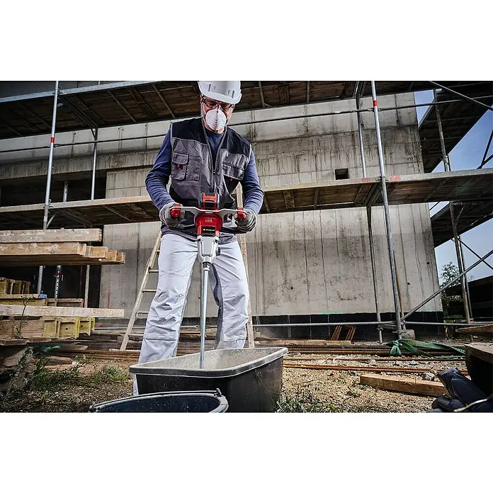 Einhell Professional Power X-Change 18V Farb- & Mörtelmischer TP-MX 18-2 Li BL Solo - 18 V, Ohne Akku, Durchmesser Rührer: 120 mm, M 14 - Ein Bauarbeiter mit Schutzhelm und Maske benutzt einen Einhell TE-MX 18 Li - Solo Mörtelrührer auf einer Baustelle.