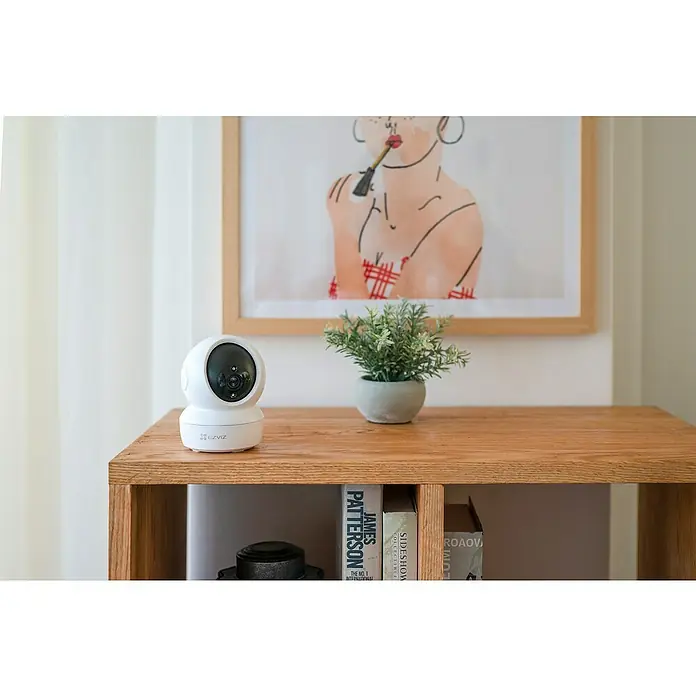 EZVIZ Überwachungskamera C6N - Weiß - Nahaufnahme einer EZVIZ-Überwachungskamera auf einem Holztisch, die Sicherheit und moderne Technologie vereint.