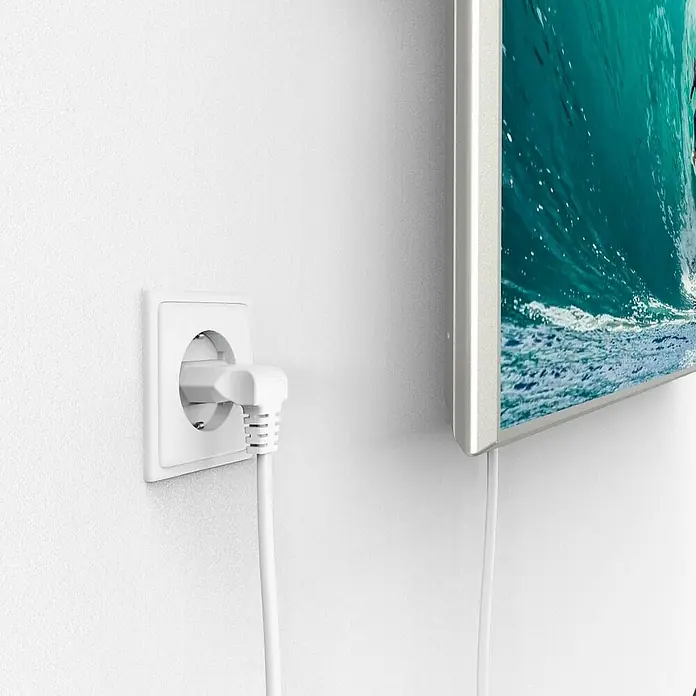Hama Netzkabel 90° gewinkelt Doppelnut C7 - Weiß, Länge: 5 m, Eurostecker, 2,5 A - Nahaufnahme eines weißen Steckers, der in eine weiße Wandsteckdose gesteckt ist, neben einem an der Wand montierten Fernseher.