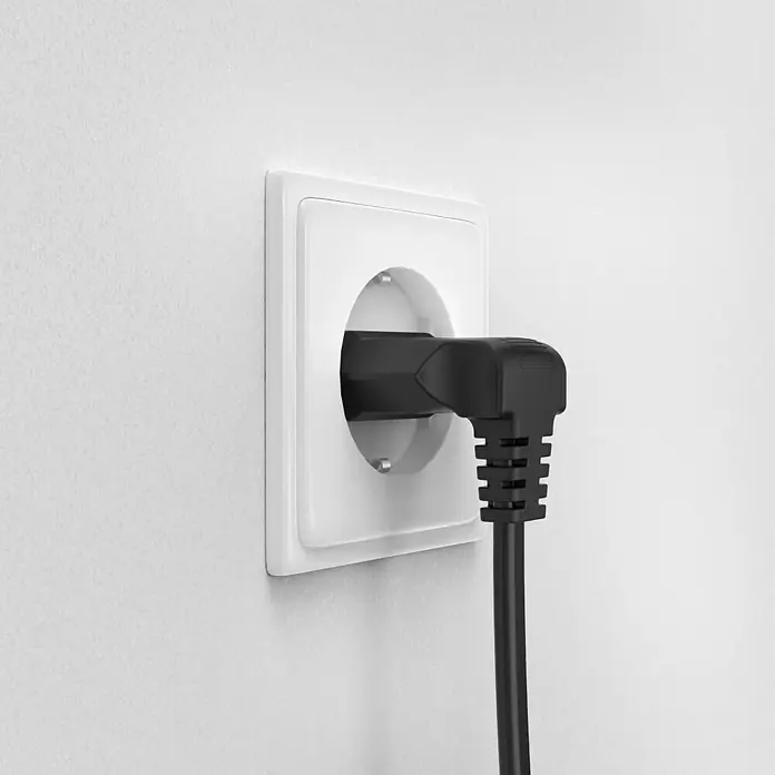 Hama Netzkabel 90° gewinkelt Doppelnut C7Schwarz, Länge: 5 m, Eurostecker, 2,5 A - Eine Nahaufnahme eines weißen Steckers an einer Wand mit einem schwarzen Netzkabel, das in die Steckdose gesteckt ist.