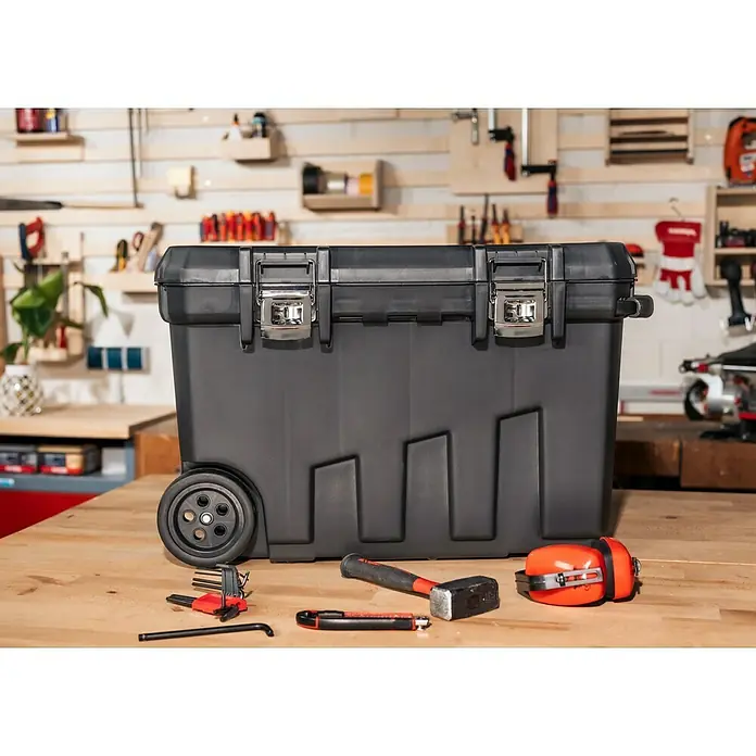 Stanley Aufbewahrungs- & Transportbox - Kunststoff, Ohne Werkzeug, Fassungsvermögen: 90 l - Eine schwarze Werkzeugkiste mit Rollen und diversen Werkzeugen auf einer Werkbank, ideal zur Aufbewahrung und zum Transport von Werkzeug.