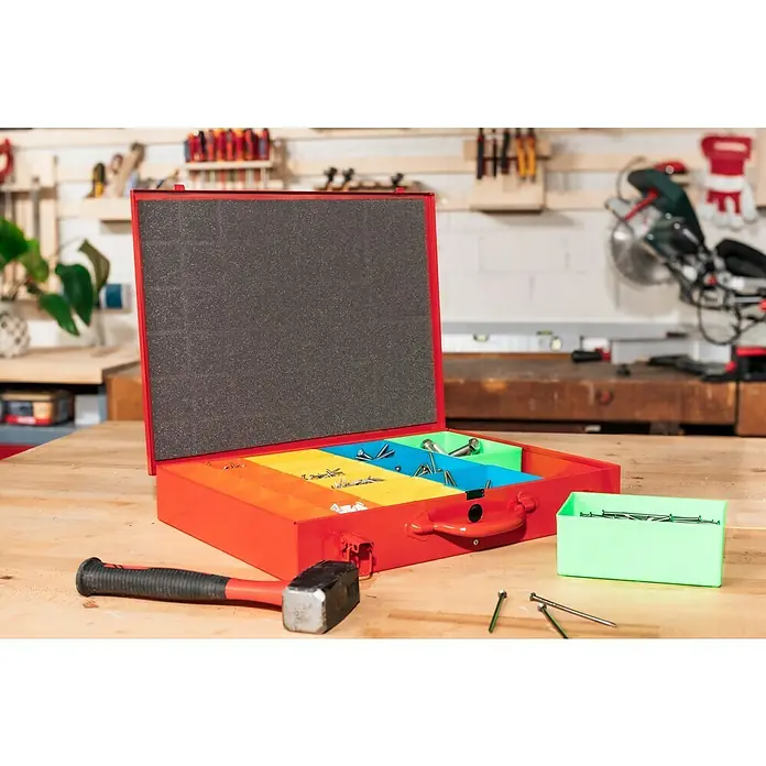 BAUHAUS Maletín organizador metálico - L x An x Al: 445 x 340 x 70 mm, Rojo - Una caja de herramientas roja con compartimentos coloridos llenos de tornillos y clavos se encuentra sobre una mesa de trabajo junto a un martillo.
