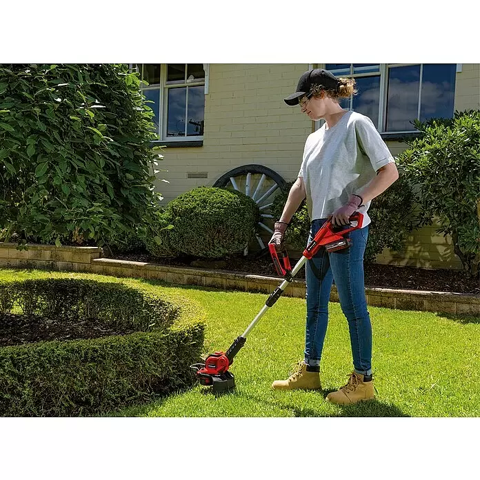 Einhell PXC 18V Akku-Rasentrimmer GE-CT18/28LI TC-Solo - 18 V, Li-Ionen, Ohne Akku, Schnittbreite Faden: 28 cm - Roter und silberner Akku-Rasentrimmer wird von einer Person zum Schneiden von Gras im Garten verwendet.