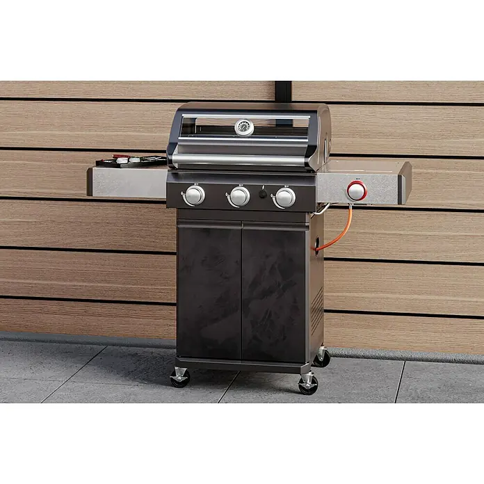Grillstar Gasgrill Powerburner 350-1 - Grillfläche (B x T): 57 x 41 cm, 8,79 kW, Anzahl Brenner: 3 - Bild einer Gasgrillstation mit drei Brennern, Seitenbrenner, schwarzen Schranktüren und einem Deckelthermometer vor einer Holzwand.
