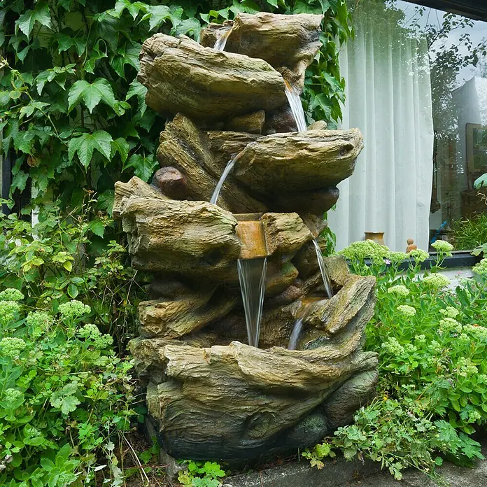 Ubbink AcquaArte Gartenbrunnen Sedona - 77 x 55 x 134 cm, Kunststoff, Grau, Braun - Nahaufnahme eines dekorativen Wasserfalls im Garten mit detaillierten Felsformationen und fließendem Wasser.