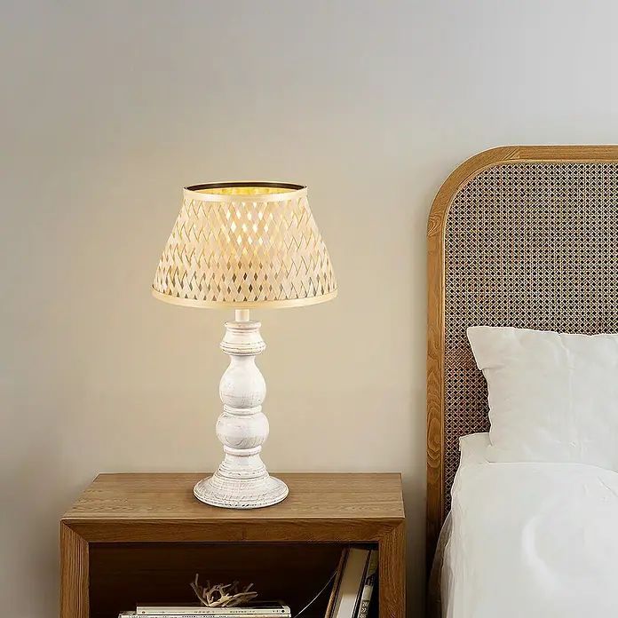 Home Sweet Home Lampenschirm Bamboo - L x B x H: 30 x 20 x 17 cm, Bambus, E27 - Eine elegante Tischlampe mit weißem Fuß und einem Lampenschirm aus hellem Bambus, die eine warme Atmosphäre im Schlafzimmer schafft.