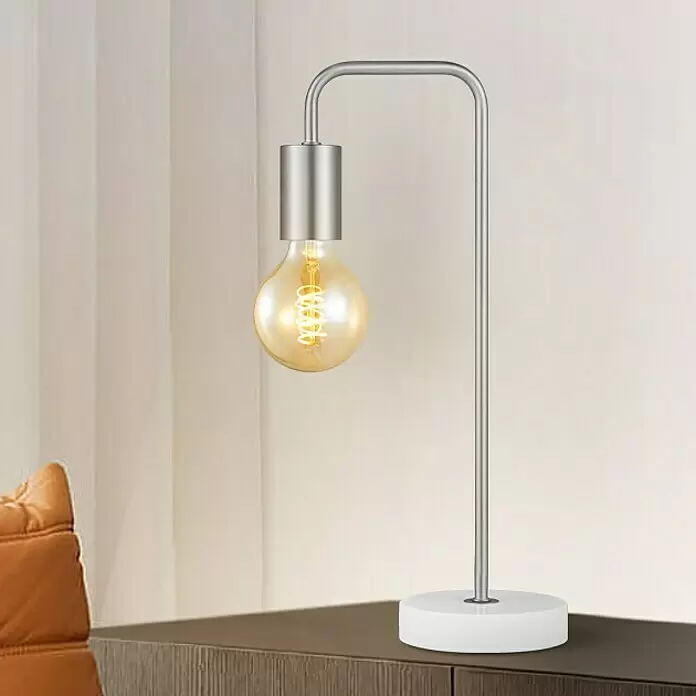 Deko-Tischleuchte Noble - 10 W, L x B x H: 20,3 x 20,3 x 40 cm, Stahl matt - Moderne Tischlampe aus silbernem Metall mit Edison-Glühbirne und weißem Sockel auf einem Holztisch.