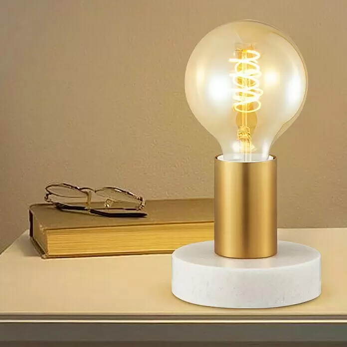 Deko-Tischleuchte Sten - 10 W, L x B x H: 10 x 9 x 9 cm, Gold - Moderne Tischlampe mit goldenem Zylinderfuß, weißem Marmorsockel und bernsteinfarbener Edison-Birne auf einem Tisch.
