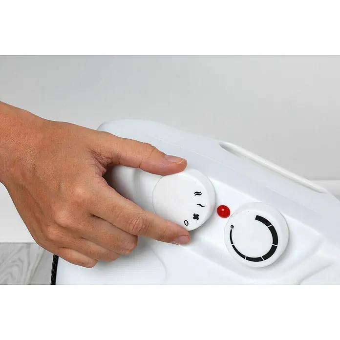 Fulmo Calefactor de aire 2 en 1 - 1.200 W, Blanco - Primer plano de una mano que utiliza un calentador blanco con dos mandos para ajustar el nivel de calor.