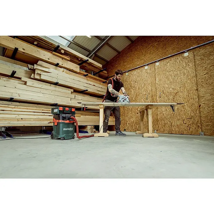 Metabo Handkreissäge KS 66FS1.500 W, Durchmesser Sägeblatt: 190 mm, Schnitttiefe bei 90 °: 66 mm - Ein Mann arbeitet in einer Werkstatt mit einer Metabo Säge an einem Stück Holz, mit einem Metabo Staubsauger im Hintergrund.