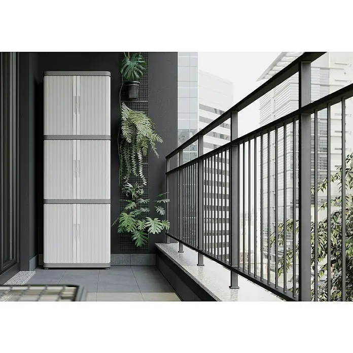Terry Kunststoff-Mehrzweckschrank Rolling Space Modular - L x B x H: 36 x 59 x 170 cm - Ein grauer Outdoor-Schrank steht auf einem Balkon, geschmückt mit Grünpflanzen und mit einem Geländer mit Blick auf Gebäude.