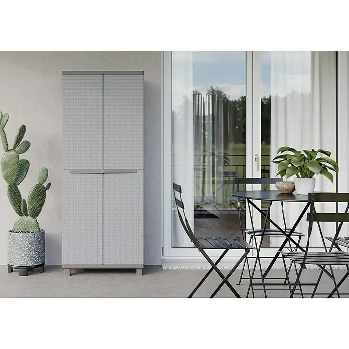 Terry Ratán Kunststoff-Mehrzweckschrank J Rattan 368 - L x B x H: 37,5 x 68 x 170 cm - Draußenaufnahme eines grauen Mehrzweckschranks mit vier Türen auf einem Balkon neben einer Kaktuspflanze und einer Tischgruppe.