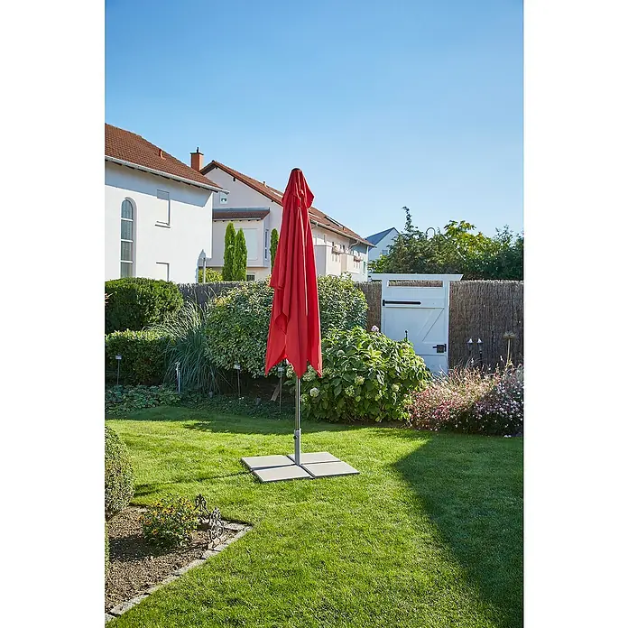 Sunfun PlattenständerFür Rohrdurchmesser: 32 mm - 48 mm, Stahl - Ansicht eines roten, geschlossenen Sonnenschirms mit viereckigem Schirmständer in einem gepflegten Garten an einem sonnigen Tag.