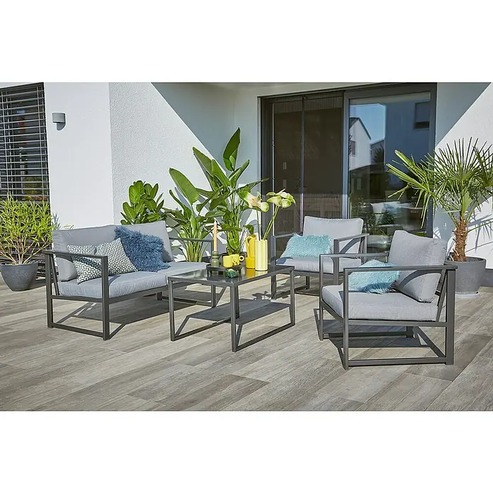 Sunfun Maja Slim Loungesofa - B x T x H: 140 x 72 x 65 cm, Anthrazit, 2-Sitzer - Moderne Terrassenmöbel-Set mit grauem Sofa, Sesseln und Tisch, umgeben von Pflanzen für eine stilvolle Outdoor-Entspannung.
