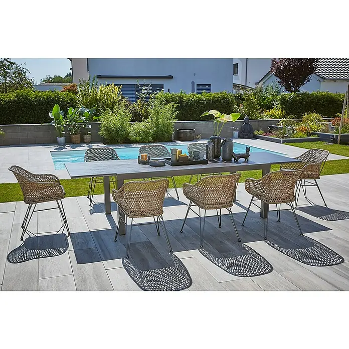 Sunfun Maja Gartenmöbel-Set Stone - 9 -tlg., Sintered Stone/Aluminium/Stahl/PE-Geflecht, Tischplatte ausziehbar, Anthrazit/Braun - Elegante Gartensitzgruppe mit Esstisch und acht Korbstühlen auf einer Terrasse mit Pool im Hintergrund.