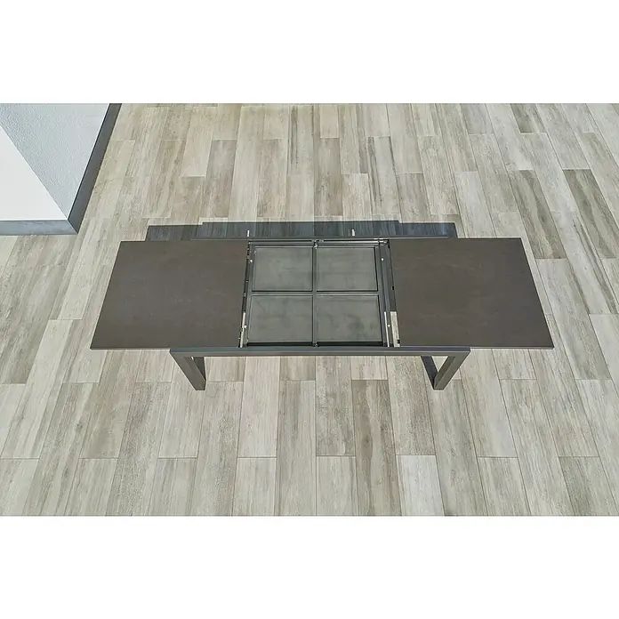 Sunfun Maja Gartentisch Stone - L x B x H: 300 x 100 x 74 cm, Aluminium, Sintered Stone, Ausziehbar, Night-Grey - Draufsicht auf einen ausziehbaren Esstisch mit dunkler Tischplatte und Metallgestell auf einem hellen Holzboden.