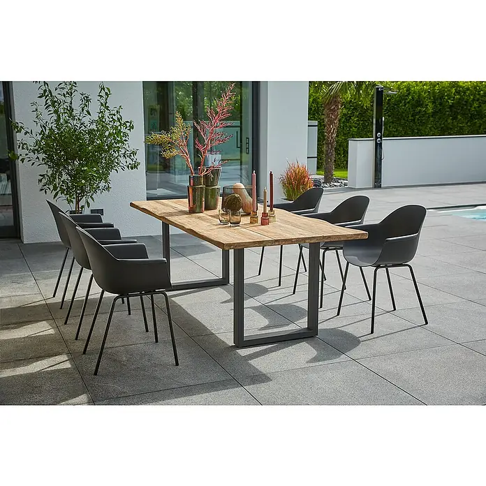 Sunfun Gartenmöbel-Set My - 8 -tlg., Baumkante/U-Gestell, Teak/Edelstahl/Kunststoff, Teak/Grau/Schwarz - Ein Gartentisch mit sechs Stühlen, dekoriert mit Vasen und Kerzen, auf einer Terrasse. Ideal für Mahlzeiten im Freien.