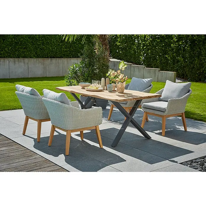 Sunfun Gartentisch - L x B x H: 180 x 90 x 75 cm, Teakholz/Edelstahl, Natur/Anthrazit, Baumkante/X-Fuß - Ein einladender Außenbereich mit einem Holztisch und vier Korbstühlen mit grauen Kissen, perfekt für Mahlzeiten im Freien und geselliges Beisammensein.