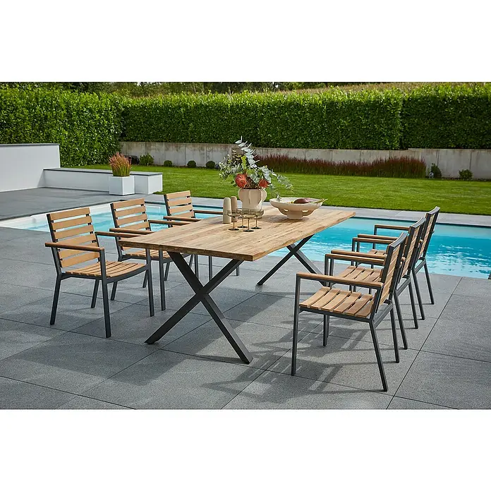 Sunfun Carina Gartenmöbel-Set - 8 -tlg., Baumkante/X-Gestell, Teak/Edelstahl/Akazie, Teak/Grau/Naturbraun - Ein Gartentisch mit sechs Stühlen steht auf einer Terrasse neben einem Pool. Der Tisch ist mit Blumen, Gläsern und einer Schale dekoriert.