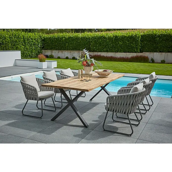 Sunfun Maja Gartenmöbel-Set - 8 -tlg., Teak/Edelstahl/Seilgeflecht, Teak/Grau/Beige, Baumkante/X-Gestell - Im Freien steht ein Esstisch mit grauen Stühlen und einem Holztisch. Der Tisch ist mit Blumen und Obst dekoriert.