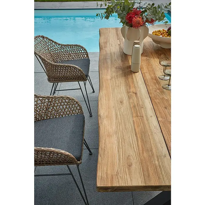 Sunfun Garten-Tischplatte220 x 100 cm, Teakholz, Baumkante - Nahaufnahme eines Gartentisches aus Holz mit zwei Stühlen, ideal für Mahlzeiten im Freien. Der Tisch besticht durch seine natürliche Holzstruktur.