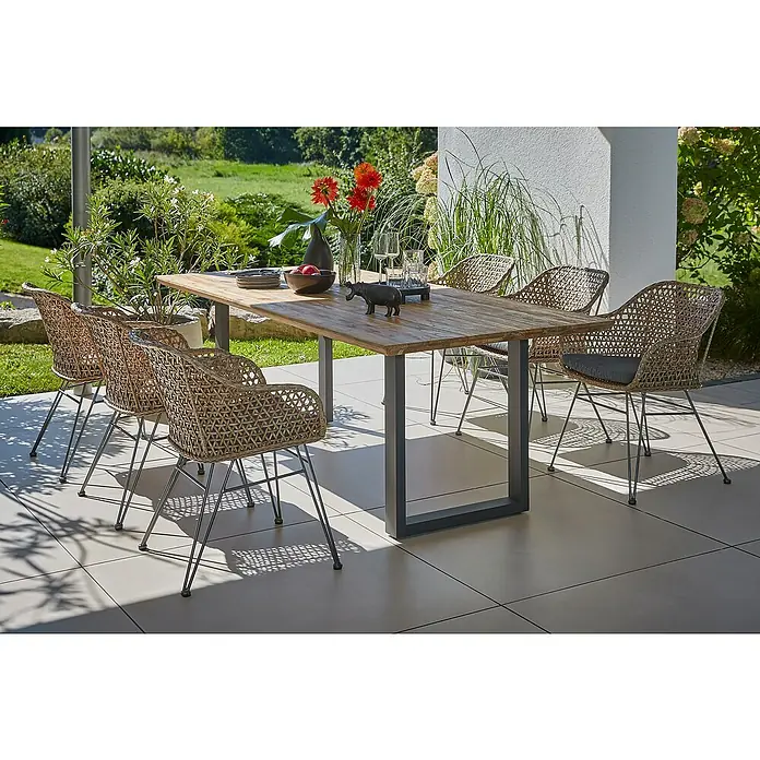 Sunfun Maja Gartenmöbel-Set - 8 -tlg., Schweizer-Kante/U-Gestell, Teak/Edelstahl/Stahl/PE-Geflecht, Teak/Grau/Braun - Ein einladender Esstisch mit sechs Korbstühlen auf einer sonnigen Terrasse, perfekt für Mahlzeiten im Freien und geselliges Beisammensein.