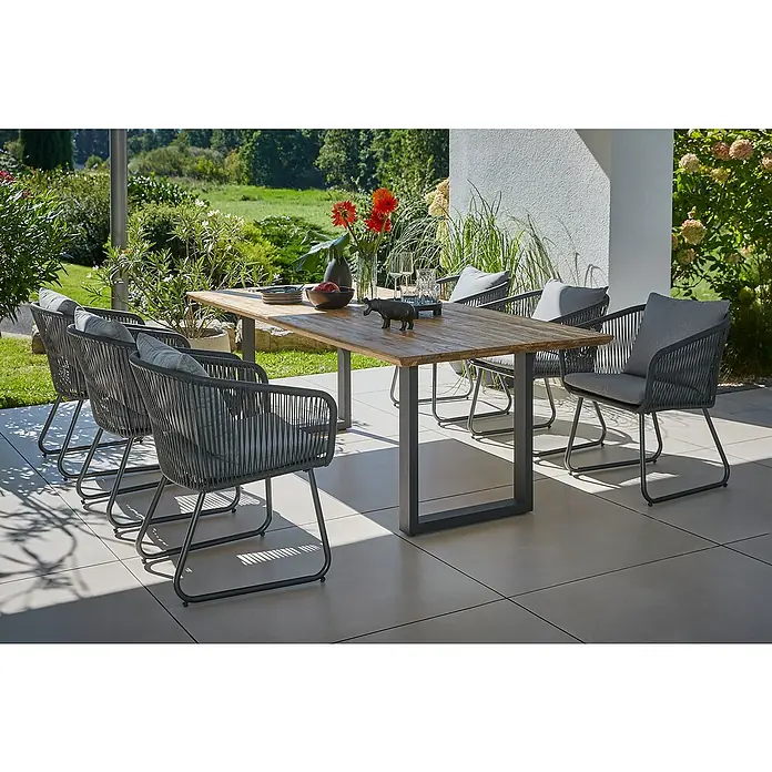Sunfun Maja Gartenmöbel-Set - 8 -tlg., Schweizer-Kante/U-Gestell, Teak/Edelstahl/Kunststofffaser-Schnüre, Teak/Grau - Eine graue Gartentischgruppe mit einem Holztisch und sechs Seilstühlen mit Kissen auf einer Terrasse.