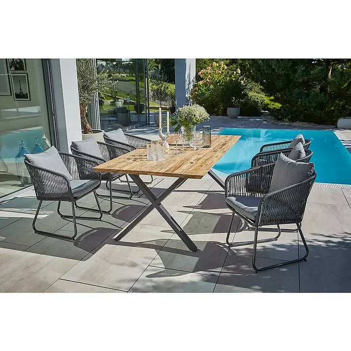 Sunfun Gartentisch - L x B x H: 220 x 100 x 75 cm, Edelstahl, Teak, Natur/Anthrazit, Schweizer Kante/X-Fuß - Das Bild zeigt einen Gartentisch mit Stühlen. Das Tischset ist aus Holz und Metall gefertigt. Es steht auf einer Terrasse neben einem Pool.