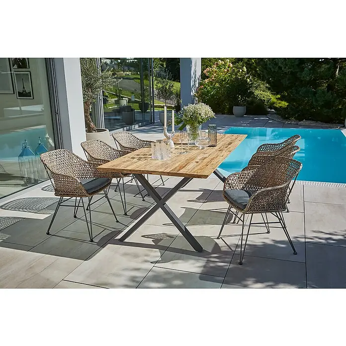 Sunfun Maja Gartenmöbel-Set - 8 -tlg., Schweizer-Kante/X-Gestell, Teak/Edelstahl/Stahl/PE-Geflecht, Teak/Grau/Braun - Gartenset mit einem Holztisch und sechs Korbstühlen mit grauen Kissen auf einer Terrasse neben einem Pool.