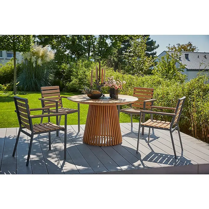 Sunfun Gartenmöbel-Set Osby/Carina - 5 -tlg., Teak/Aluminium/Akazie/Stahl, Teak/Anthrazit - Ein runder Esstisch mit vier Stühlen steht auf einer Terrasse, umgeben von üppigem Grün. Das Möbelset ist perfekt für Mahlzeiten im Freien.