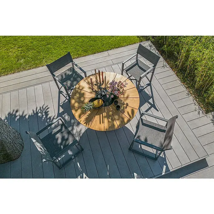 Sunfun Gartenmöbel-Set Osby/Maja II - 5 -tlg., Teak/Aluminium/Textilen, Teak/Anthrazit - Ein runder Esstisch aus Holz mit vier Stühlen auf einer Terrasse mit Gras und Bambus im Hintergrund.