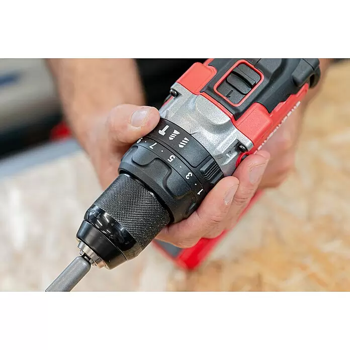 Powerworks -  - Eine Hand hält einen rot, schwarz und silbernen Akkubohrschrauber und verstellt den Drehmomentring. Ein Metallbit steckt im texturierten Bohrfutter.