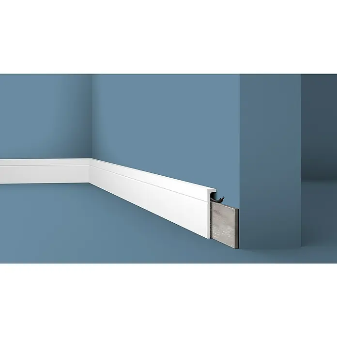 Nmc Decoflair Fußleiste Abdeckfußleiste CBC2 - 2 m x 2,2 cm x 11 cm, Hochverdichtetes extrudiertes Polymer (HDPS), 1 Stk. - Das Bild zeigt eine weiße Fußleiste, die an einer blauen Wand befestigt ist. Die Leiste ist sauber verarbeitet und hat eine praktische Kabelführung.