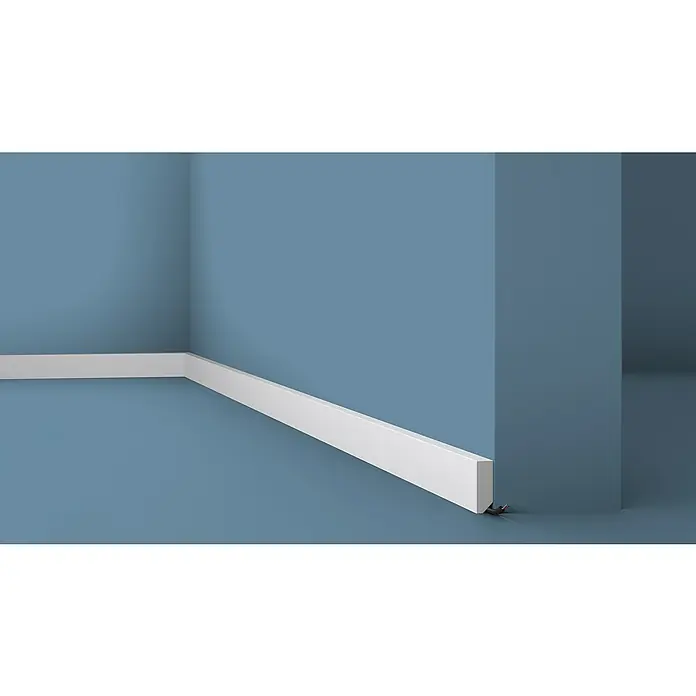 Nmc Decoflair Zierprofil M38 - 2 m x 1,3 cm x 3,8 cm, Hochverdichtetes extrudiertes Polymer (HDPS) - Detailaufnahme einer blauen Wand mit weißer Fußleiste, die einen sauberen und modernen Übergang zum Boden bildet.