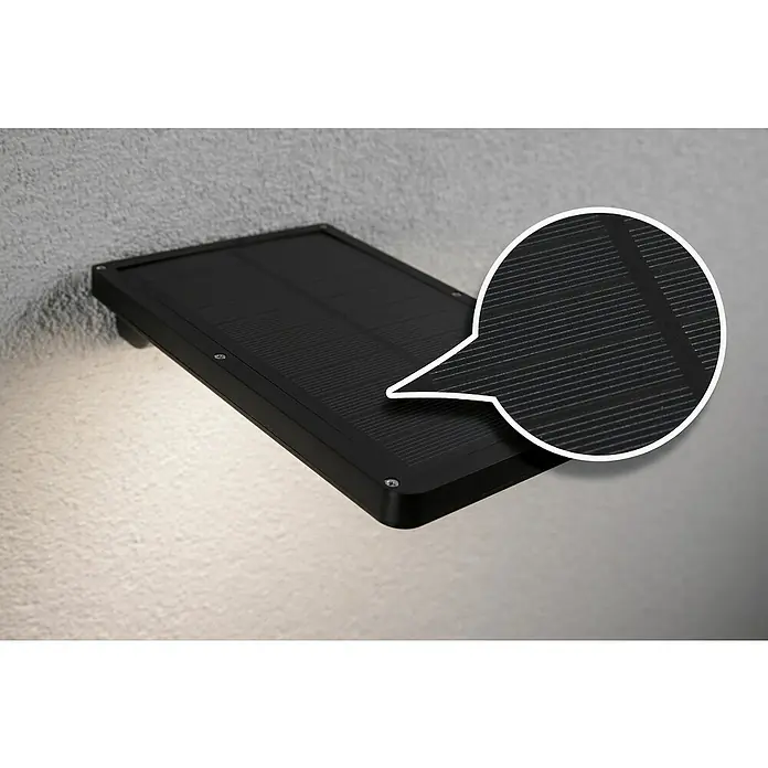 Paulmann Solar-Außenwandleuchte Solveig - Max. Systemleistung: 4,8 W, L x B x H: 17,3 x 10,5 x 2,9 cm, Schwarz, Lichtstrom: 338 lm - Nahaufnahme einer schwarzen Solarleuchte an einer Wand mit Lupeneffekt, der die Solarzellenstruktur hervorhebt.