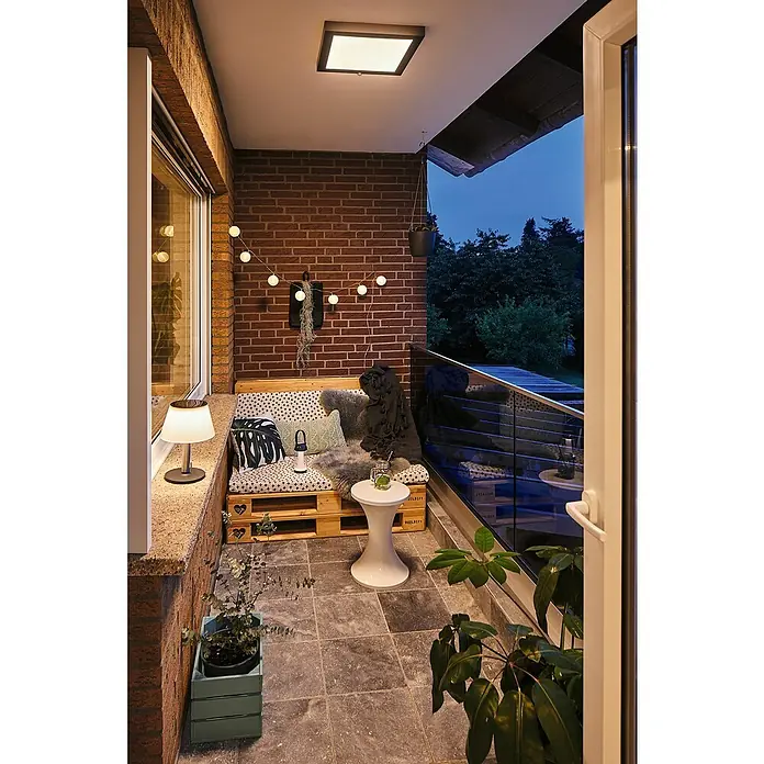 Paulmann Akku-Tischleuchte Cupulino - 1,3 W, Anthrazit, Warmweiß, 8,3 x 18,4 cm - Ein gemütlicher Balkon mit Palettenmöbeln, Kissen und Pflanzen, beleuchtet durch eine moderne Deckenleuchte und eine Tischlampe.