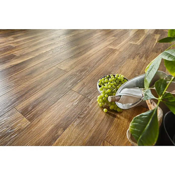LOGOCLIC Laminatmuster Vinto Hickory Marsala - 296 x 195 x 1 mm, Landhausdiele - Eine Nahaufnahme von einem hellbraunen Holzboden mit einer Flasche Wein, Trauben und einer Topfpflanze. Der Boden hat eine natürliche Holzmaserung.