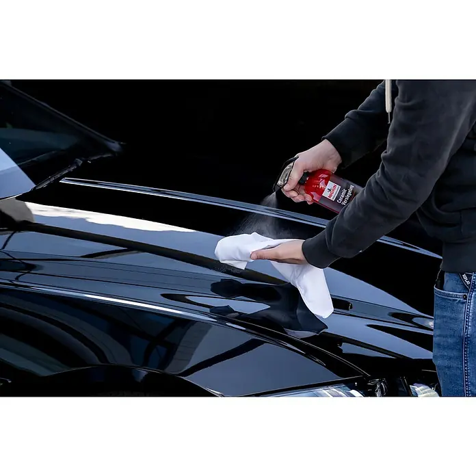 Nigrin Performance Versiegelung Ceramic - 750 ml - Detailaufnahme einer Person, die mit Nigrin Keramik Versiegelung ein Auto reinigt, wobei der Fokus auf dem Produkt und der glänzenden Oberfläche liegt.