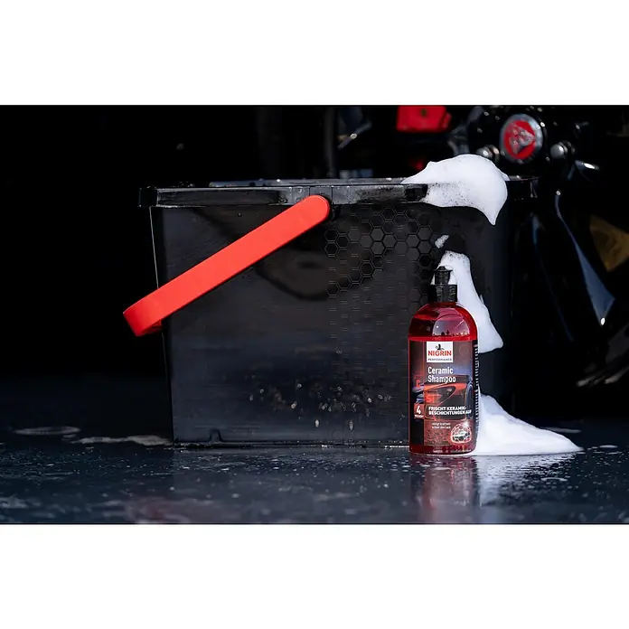 Nigrin Performance Auto-Shampoo Ceramic - 500 ml - Nahaufnahme von Nigrin Ceramic Shampoo neben einem Eimer mit Schaum, ideal für die Autowäsche und Lackpflege.