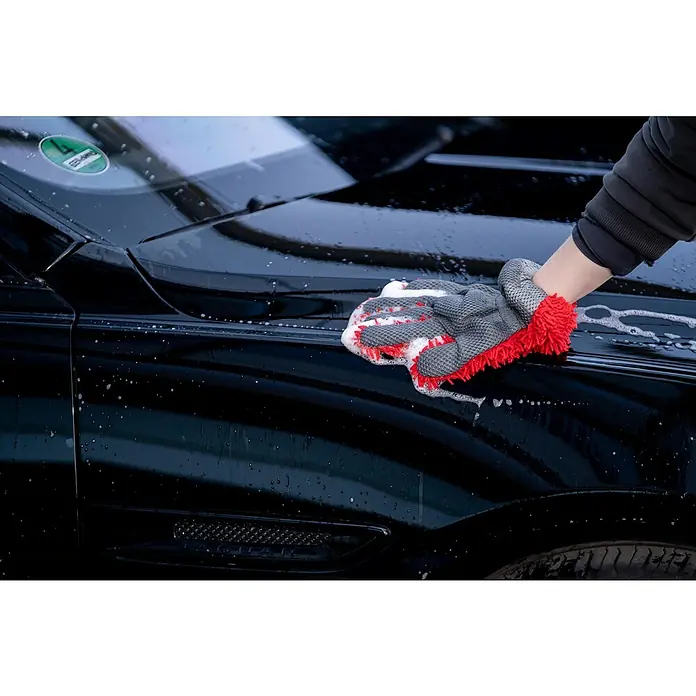 Nigrin Performance Auto-Shampoo Ceramic - 500 ml - Das Bild zeigt einen Waschhandschuh in Grau und Rot, der zum Reinigen eines schwarzen Autos verwendet wird, um Sauberkeit und Pflege hervorzuheben.