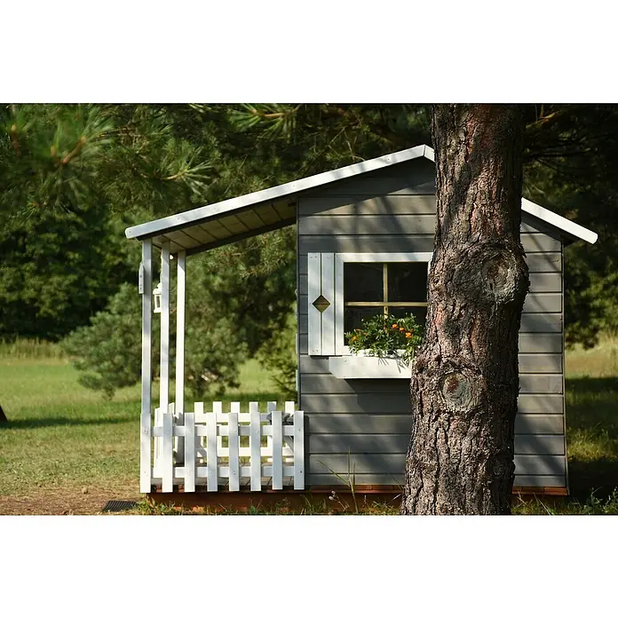 Spielhaus Mia - L x B x H: 190,5 x 143 x 159 cm, Holz, Natur - Ein charmantes Spielhaus im Garten, umgeben von üppigem Grün, lädt Kinder zum fantasievollen Spielen und Entdecken in der Natur ein.
