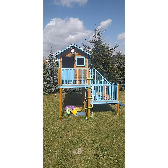 Spielhaus Tom 60 - L x B x H: 226,5 x 176 x 272 cm, Holz, Natur/Rot - Ein farbenfrohes Spielhaus aus Holz mit Leiter, Treppe und blauen Akzenten steht auf einer grünen Wiese.