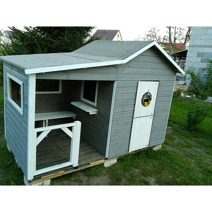 Spielhaus Elisa - L x B x H: 240 x 125 x 173 cm, Holz, Natur - Ein graues Kinderspielhaus mit weißem Rahmen, kleinem Fenster und halber Tür mit einem Blumenkranz darauf, steht im Garten.