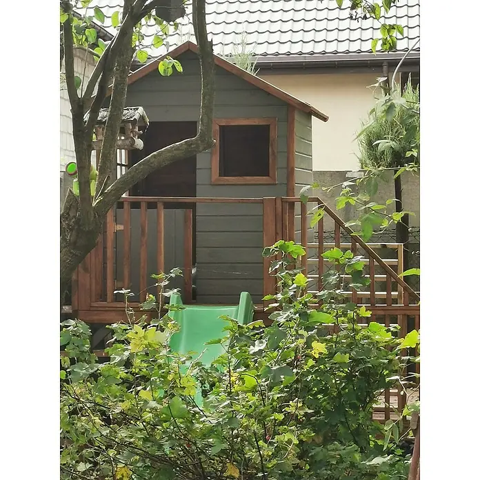 Spielhaus Tom mit Rutsche - L x B x H: 226,5 x 176 x 272 cm, Holz, Natur - Ein malerisches Spielhaus mit Rutsche im Garten, umgeben von üppigem Grün, das zu fantasievollen Abenteuern im Freien einlädt.